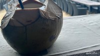 Nikmat kelapa muda tambah nikmat di tepi pantai Bali.