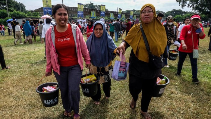 Warga menerima paket sembako dan makanan ringan dari Komunitas Solo Bersama Selamanya di Benteng Vastenburg, Solo, Minggu (23/3/2025). Panitia setempat mengaku membagikan total sebanyak 10.000 bingkisan Lebaran secara cuma-cuma kepada masyarakat yang membutuhkan untuk merayakan kebahagiaan bersama menjelang momen Lebaran 2025.