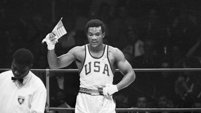 george foreman olimpiade 1968 tinju tinju kelas berat (Original Caption) 10/26/1968-Mexico City, Mexico- George Foreman of Houston, TX, waves a small American flag after he won the Olympics heavyweight boxing gold medal to climax America's greatest effort at an Olympics. The US walked away with 45 gold medals, 27 silvers and 34 bronze. Foreman scored a second-round technical knockout over Ionas Chepulis of the Soviet Union.