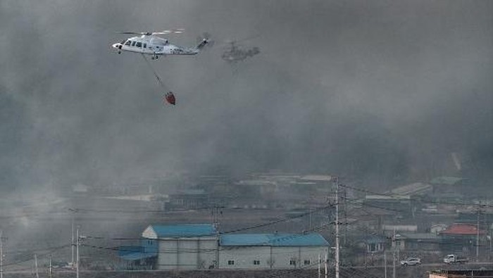 Helicopters try to extinguish a fire after a wildfire broke out in the southeastern county of Uiseong on March 22, 2025. At least two firefighters have been killed in a wildfire in South Korea and more than 200 residents in 15 southern villages have been told to evacuate, authorities said on March 22. (Photo by YONHAP / AFP) / - South Korea OUT / NO ARCHIVES -  RESTRICTED TO SUBSCRIPTION USE