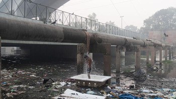 Seorang pria terlihat mandi saat air bocor dari pipa di New Delhi, India. Foto: Boredpanda