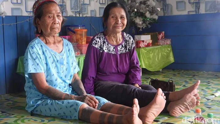Di Desa Sungai Urang, Kabupaten Bulungan, Kalimantan Utara, sebuah rumah adat berdiri sederhana di tepi jalanan berbatu. Di samping bangunan tersebut, Lem Dungau, seorang nenek duduk dengan tenang.