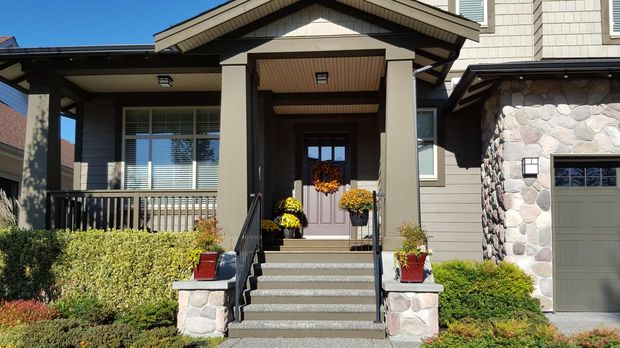 Fort Langley,British Columbia, Canada- October 2,2017: Front entrance to Modern Shingle and stone style home. Autumn flowers and arrangements on stairs,porch and door.