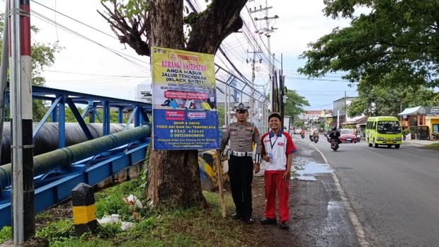 Kanit Kamsel Satlantas Polres Pasuruan Kota memasang baliho di Jalan Raya Pleret