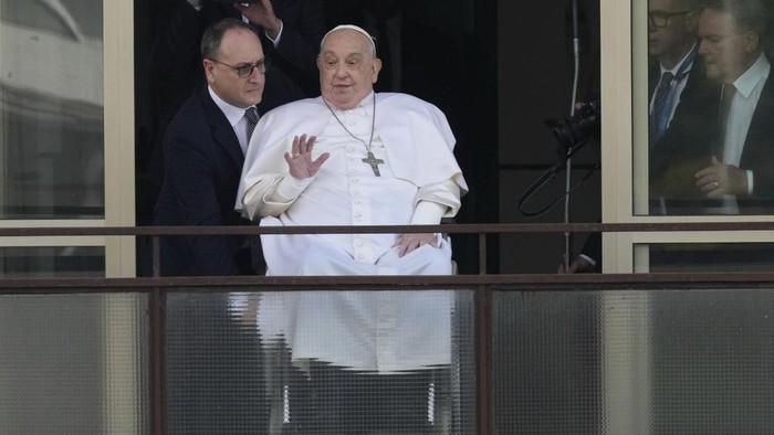 Pope Francis waves as he appears at a window of the Agostino Gemelli Polyclinic in Rome, Sunday, March 23, 2025, where he has been treated for bronchitis and bilateral pneumonia since Feb. 14. (AP Photo/Andrew Medichini)