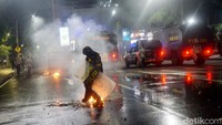 Polisi memadamkan api dari water barrier yang dibakar massa aksi.