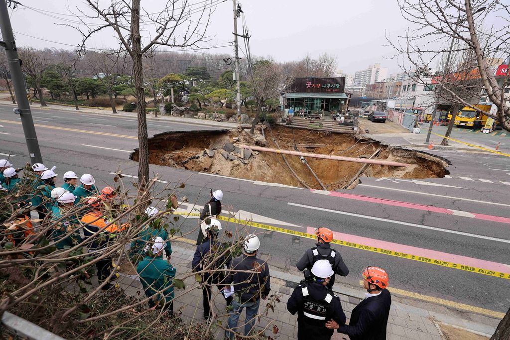 Emergency workers stand near a sinkhole in a road, in Seoul, South Korea, March 25, 2025. Yonhap via REUTERS