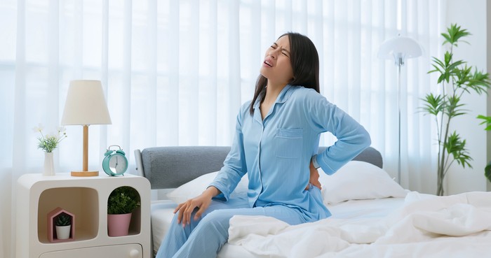 Asian woman wake up in the morning with back pain - she did not sleep well