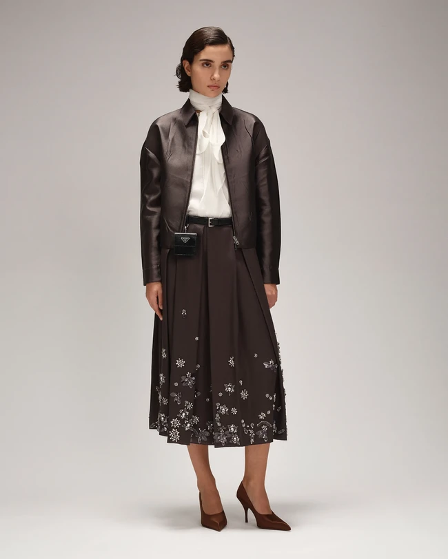 Prada menghadirkan estetika minimal-maksimal dalam koleksi Ramadan dengan sentuhan elegan dan cermat. Koleksi wanita menampilkan rok lipit klasik dalam nuansa abu-abu, burgundy, dan beige, diperkaya payet serta kilau mewah, sementara gaun dan rok sutra panjang dengan hiasan kristal dan cermin menawarkan kesan dramatis. (Foto: Dok. Prada)