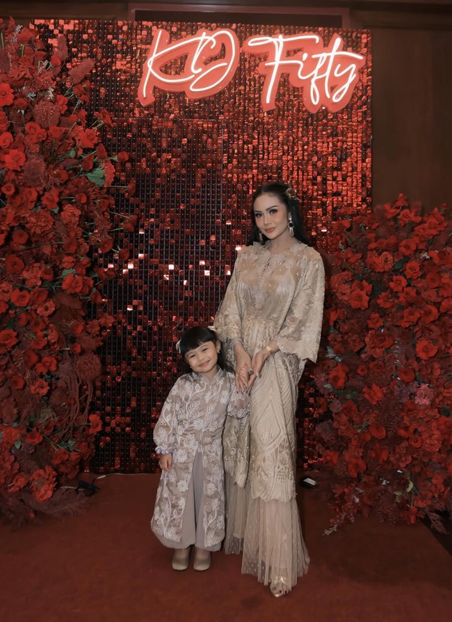 Rambut panjangnya tampak dibiarkan terurai dengan salah satu sisi dihiasi jepit rambut berbentuk bunga warna coklat keemasan. Ia juga mengenakan sepasang anting gantung warna emas. Foto: Instagram/@krisdayantilemos