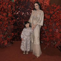 Rambut panjangnya tampak dibiarkan terurai dengan salah satu sisi dihiasi jepit rambut berbentuk bunga warna coklat keemasan. Ia juga mengenakan sepasang anting gantung warna emas. Foto: Instagram/@krisdayantilemos