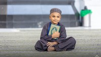 Seorang anak laki-laki mendekap erat Al-Quran. Senyum tampak merekah di bibirnya. Foto: Kementerian Haji dan Umrah Arab Saudi