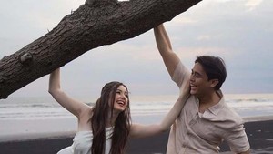 Vika tampil anggun dengan gaun putih panjang, sementara Billy terlihat santai dengan celana pendek putih dan kemeja pastel. Foto: Instagram Vika Kolesnaya