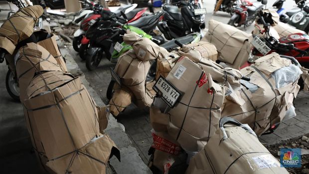 Pekerja membungkus sepeda motor dengan kardus di jasa pengiriman barang di kawasan Pasar Senen, Jakarta, Rabu (26/3/2025). (CNBC Indonesia/Tri Susilo)
