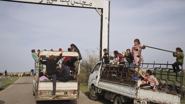 Local residents wait on the side of the road to be evacuated due to fears of Israeli army incursions, following a drone attack that reportedly killed at least four people in the area, on the outskirts of the village of Koayiah, southwestern Syria, Tuesday, March 25, 2025. (AP Photo/Omar Albam)
