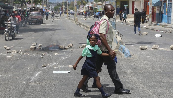 A local gestures on a street blocked by burning tires and debris during a demonstration demanding the resignation of the transitional presidential council, in Port-au-Prince, Haiti, Wednesday, March 26, 2025. (AP Photo/Odelyn Joseph)
