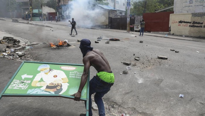 A local gestures on a street blocked by burning tires and debris during a demonstration demanding the resignation of the transitional presidential council, in Port-au-Prince, Haiti, Wednesday, March 26, 2025. (AP Photo/Odelyn Joseph)