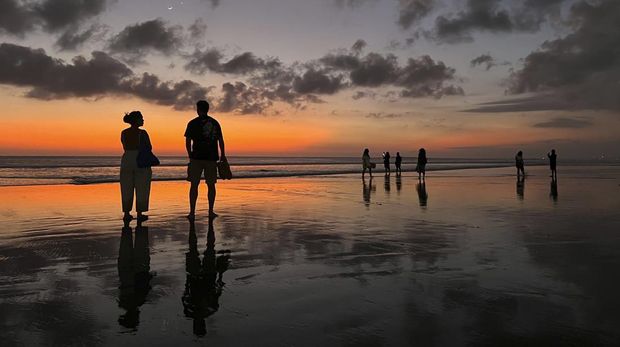 Tourists enjoy the sunset on Seminyak Beach in Bali on Thursday, Sept. 5, 2024 (AP Photo/Adam Schreck)