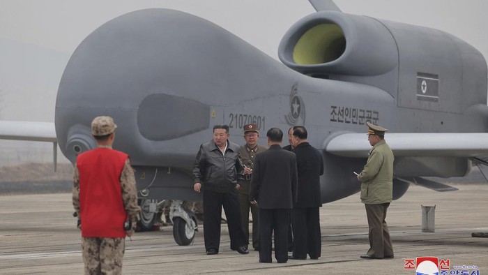 Kim Jong Un Pimpin Uji Coba Drone Militer Korut In this photo provided Thursday, March 27, 2025, by the North Korean government, a man in a military uniform films what is called an attack drone crashing into a prepared target at an undisclosed location in North Korea, earlier this week. Independent journalists were not given access to cover the event depicted in this image distributed by the North Korean government. The content of this image is as provided and cannot be independently verified. Korean language watermark on image as provided by source reads: