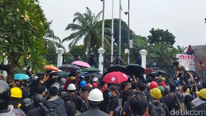 Massa kompak buka payung saat disemprot water canon saat demo tolak UU TNI di DPR