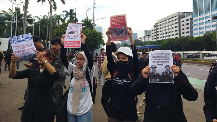 Massa membawa poster penolakan pengesahan RUU TNI saat aksi di depan Gedung DPR/MPR/DPD RI. (Kurniawan/detikcom)