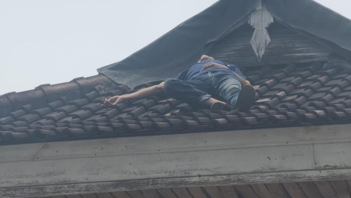 Seorang pria, T, yang tertidur di gnting rumah warga di Denpasar Timur, Rabu (26/3/2025) siang. Sebelumnya, T dikejar warga karena mencurigakan.