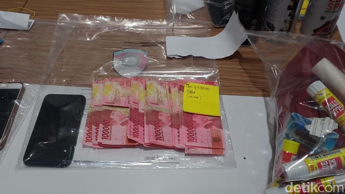 Uang palsu dan ponsel yang diamankan sebagai barang bukti di Polres Kota Batu