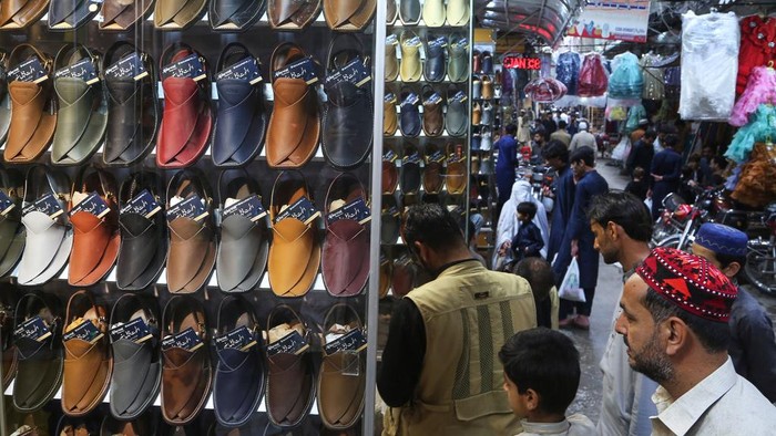 People browse traditional shoes at a market as they shop for the upcoming Eid al-Fitr celebrations, which marks the end of the Islamic holy month of Ramadan, in Peshawar, Pakistan, Wednesday, March 26, 2025. (AP Photo/Muhammad Sajjad)