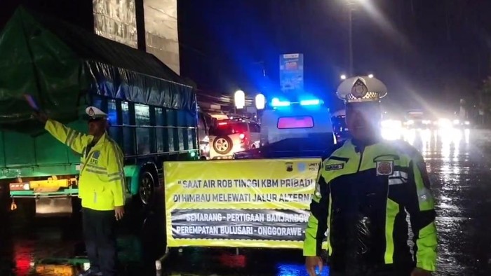 Petugas Polsek Genuk mengatur lalulintas di Simpang Genuksari karena ada rob di Sayung, Jumat (28/3/2025).
