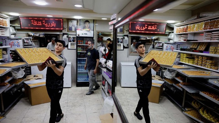 A worker carries traditional sweets as Palestinians prepare for the upcoming holiday of Eid al-Fitr marking the end of Ramadan, in Jerusalem Old City, March 27, 2025.REUTERS/Ammar Awad     TPX IMAGES OF THE DAY