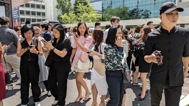 People stand outside an office building in Bangkok on March 28, 2025 after an earthquake. A powerful 7.7 magnitude earthquake hit central Myanmar on March 28, with tremors felt south into Thailand, with residents in the capital Bangkok runing into the streets as buildings shook. (Photo by Candida NG / AFP)