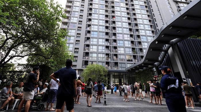 People gather outside a building after a strong earthquake struck central Myanmar on Friday, earthquake monitoring services said, which affected Bangkok as well with hundreds of people pouring out of buildings in the Thai capital in panic after the tremors, in Bangkok, Thailand, March 28, 2025. REUTERS/Chalinee Thirasupa