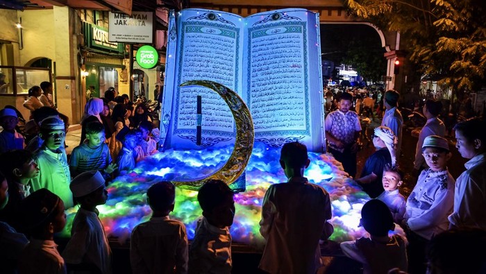 Anak-anak berada dekat replika Al Quran saat takbir keliling di kawasan kota tua Ampenan, Mataram, NTB, Minggu (30/3/2025). Takbir keliling tersebut dalam rangka menyambut Hari Raya Idul Fitri 1446 H yang jatuh pada hari Senin (31/3). ANTARA FOTO/Ahmad Subaidi/agr