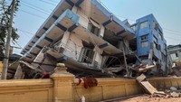 Bangunan-bangunan di sepanjang jalan terlihat hancur dan miring ke satu sisi akibat gempa. 