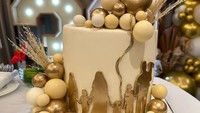 Perayaannya menghadirkan kue dengan nuansa emas. Hiasannya menyerupai balon berwarna emas dan siluet keluarga mereka. Foto: Instagram/YouTube Kartika Putri
