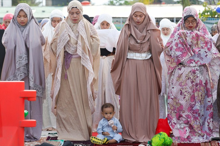 A boy and Muslim women attend mass prayers at the Sunda Kelapa port during Eid al-Fitr, marking the end of the holy fasting month of Ramadan in Jakarta, Indonesia, March 31, 2025. REUTERS/Ajeng Dinar Ulfiana