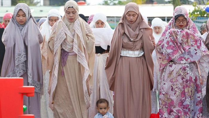 A boy and Muslim women attend mass prayers at the Sunda Kelapa port during Eid al-Fitr, marking the end of the holy fasting month of Ramadan in Jakarta, Indonesia, March 31, 2025. REUTERS/Ajeng Dinar Ulfiana