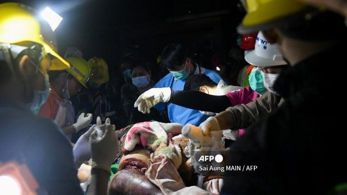EDITORS NOTE: Graphic content / Doctors and medics teams treat a victim trapped under the rubble of the destroyed Sky Villa Condominium development building in Mandalay on March 30, 2025. (Photo by Sai Aung MAIN / AFP)