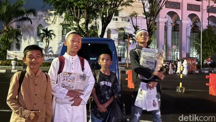 Penjual koran saat salat Id di Masjid Agung Palembang yang meraih cuan.