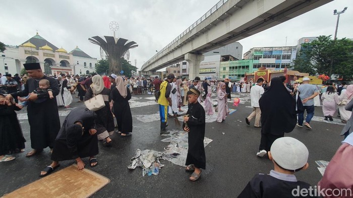 Petugas kebersihan memunguti sampah yang bertebaran di sekitar Masjid Agung Palembang.