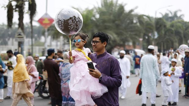 Seorang pria dengan seorang anak menghadiri rapat umum Idul Fitri untuk menandai berakhirnya bulan suci Ramadan, di Dhaka, Bangladesh, 31 Maret 2025. (REUTERS/Mohammad Ponir Hossain)