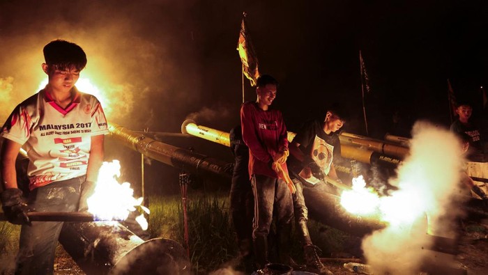 Tradisi Tembak Meriam Malaysia Meriahkan Perayaan Idul Fitri Villagers hold torches to light steel cannons as part of a tradition to welcome Eid al-Fitr on the eve of the celebration in Kuala Kangsar, Malaysia, on March 30, 2025. REUTERS/Hasnoor Hussain