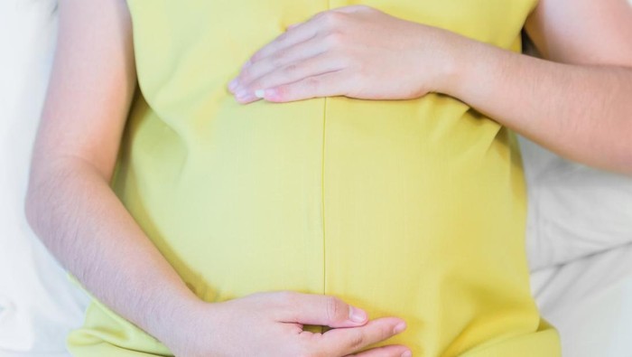 Ilustrasi hamil besar Pregnant woman touching her belly sitting on the bed in bedroom