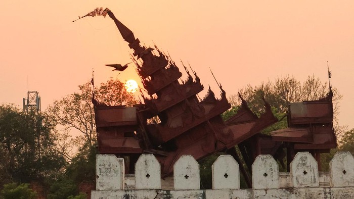 A bird flies past the damaged Mandalay Palace during sunset in Mandalay on March 31, 2025, three days after the deadly Myanmar earthquake. Myanmar declared a week of national mourning on March 31 for the countrys devastating earthquake, as the death toll passed 2,000 and hopes faded of finding more survivors in the rubble of ruined buildings. (Photo by Sebastien BERGER / AFP)