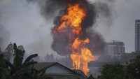 Api menjulang tinggi di atas distrik permukiman. Orang-orang pun mengungsi akibat peristiwa itu. AP Photo/Vincent Thian