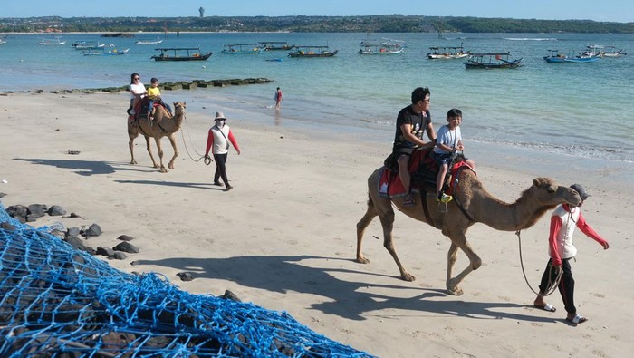 Wisatawan nusantara menikmati suasana pantai dengan menaiki unta pada liburan Idul Fitri di Pantai Kelan, Badung, Bali, Selasa (1/4/2025). Pengelola wisata naik unta di pantai itu mengatakan pada liburan Idul Fitri 1446 Hijriah jumlah wisatawan nusantara yang menyewa wahana tersebut sekitar 60-70 orang per hari dengan harga sewa Rp150 ribu hingga Rp200 ribu sesuai durasi yang telah ditentukan. ANTARA FOTO/Nyoman Hendra Wibowo/nym.