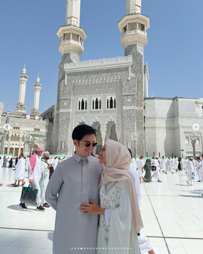 Pasangan pengantin baru Angga Yunanda dan Shenina Cinnamon merayakan Lebaran pertama mereka sebagai suami-istri di Tanah Suci. Menyampaikan ucapan Lebaran dengan foto latar Masjidil Haram, keduanya kompak memakai busana gamis, Angga gamis pria warna silver, sedangkan Shenina gamis putih dengan detail daun silver. Foto: Dok. Instagram