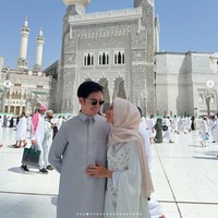 Pasangan pengantin baru Angga Yunanda dan Shenina Cinnamon merayakan Lebaran pertama mereka sebagai suami-istri di Tanah Suci. Menyampaikan ucapan Lebaran dengan foto latar Masjidil Haram, keduanya kompak memakai busana gamis, Angga gamis pria warna silver, sedangkan Shenina gamis putih dengan detail daun silver. Foto: Dok. Instagram