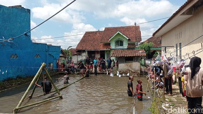 Keseruan masyarakat Kampung Cilenga ikut perlombaan meniti bambu di atas kolam.