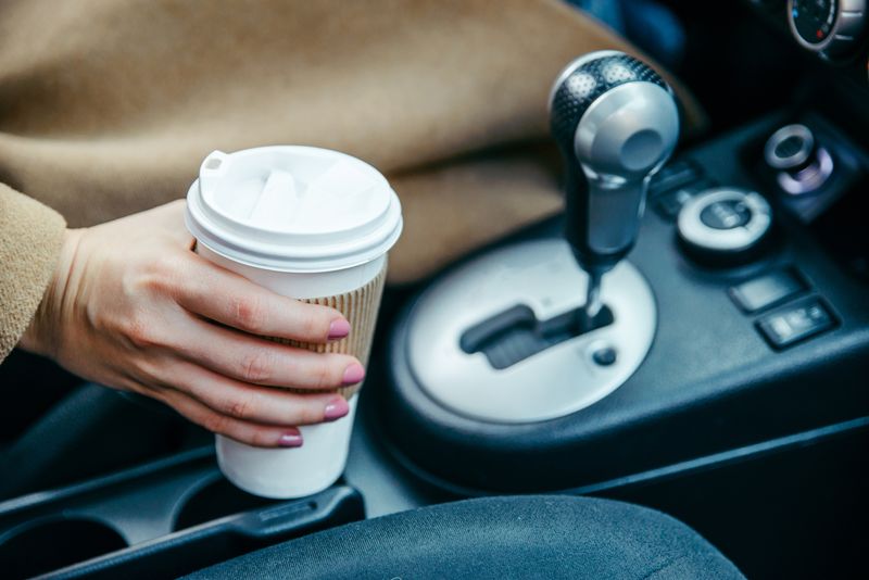woman hand taking cup with coffee in car. close up. crop. morning energy. lifestyle